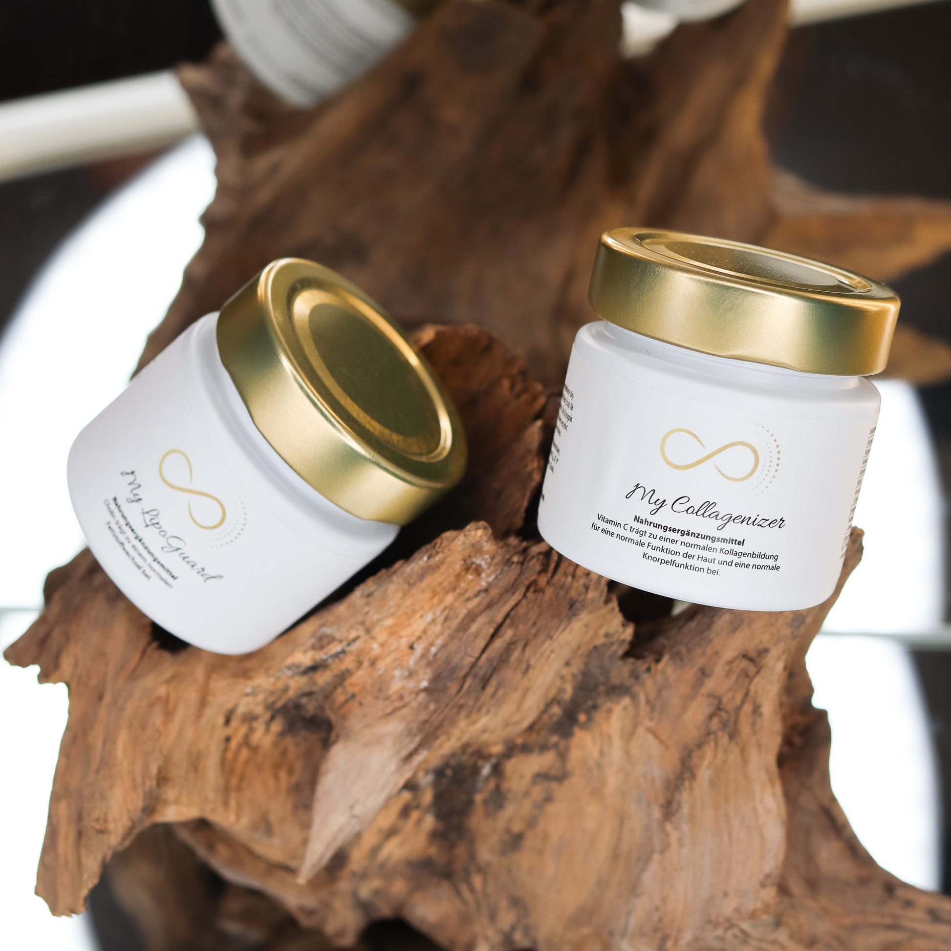 Produktbild zweier Nahrungsergänzungsmittel im weißen Glas mit goldenem Deckel, dekorativ auf einem Naturholz-Element arrangiert. Sichtbar sind die Produkte „My LipoGuard“ und „My Collagenizer“ aus der ANS Nutrivity Secrets Serie. Das Bild dient der hochwertigen Visualisierung der Verpackung. Alle Angaben zu Inhaltsstoffen und Anwendung befinden sich in der jeweiligen Produktbeschreibung im Shop.
