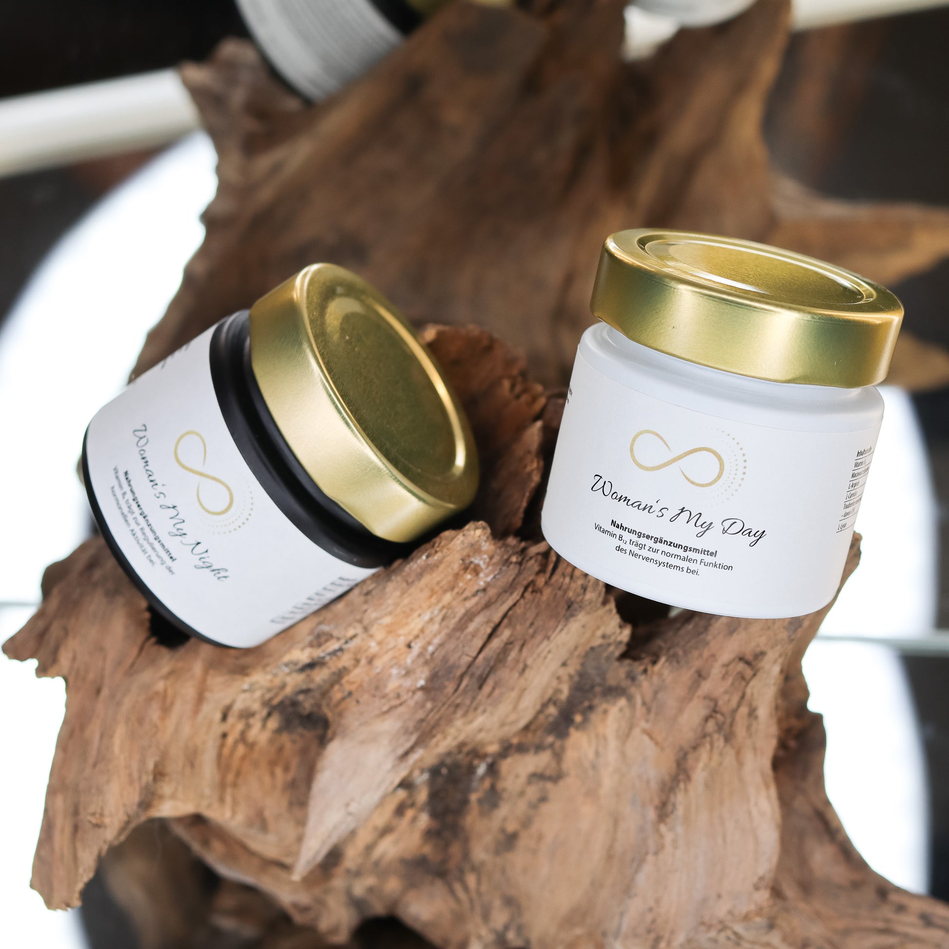 Produktbild zweier Nahrungsergänzungsmittel im weißen Glas mit goldenem Deckel, dekorativ auf einem Naturholz-Element arrangiert. Sichtbar sind die Produkte „Womans My Night“ und „Womans My Day“ aus der ANS Nutrivity Secrets Serie. Das Bild dient der hochwertigen Visualisierung der Verpackung. Alle Angaben zu Inhaltsstoffen und Anwendung befinden sich in der jeweiligen Produktbeschreibung im Shop.