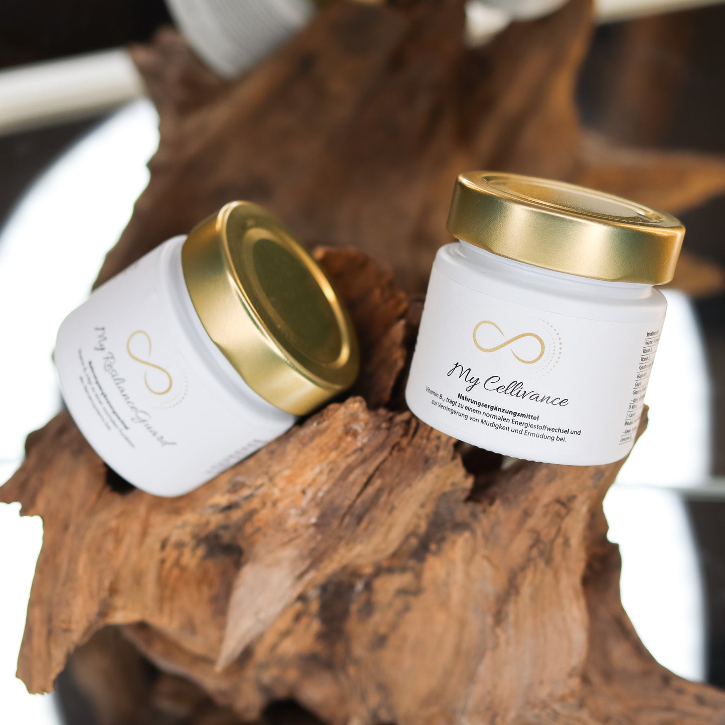 Produktbild zweier Nahrungsergänzungsmittel im weißen Glas mit goldenem Deckel, dekorativ auf einem Naturholz-Element arrangiert. Sichtbar sind die Produkte „My ResilianceGuard“ und „My Cellivance“ aus der ANS Nutrivity Secrets Serie. Das Bild dient der hochwertigen Visualisierung der Verpackung. Alle Angaben zu Inhaltsstoffen und Anwendung befinden sich in der jeweiligen Produktbeschreibung im Shop.