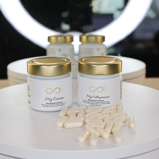 Produktfoto von zwei Nahrungsergänzungsmitteln aus dem ANS Nutrivity Secrets Sortiment - empfohlen von Katja Rückemann. Abgebildet sind zwei weiße Glastiegel mit goldfarbenem Deckel und schlichter Etikettierung, vorne dekorativ arrangierte weiße Kapseln. Im Set enthalten sind die Produkte „My Collagenizer“ und „My Cesara“. Alle detaillierten Angaben zu Wirkstoffen und Inhaltsstoffen finden sich auf den jeweiligen Produktseiten im Online-Shop.