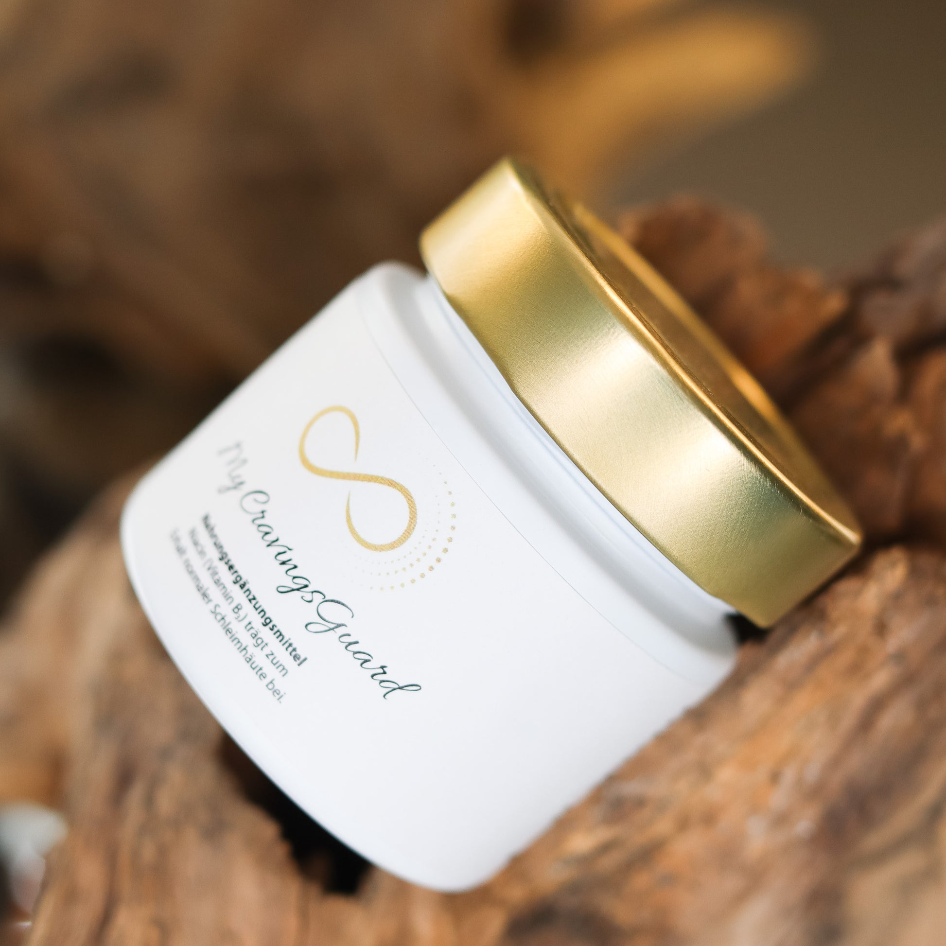 Produktbild eines Nahrungsergänzungsmittels im weißen Glas mit goldenem Deckel, liegend auf natürlichem Holzuntergrund. Abgebildet ist das Produkt „My GravingsGuard“ aus der ANS Nutrivity Secrets Serie – hochwertiges Supplement, fotografiert zur Veranschaulichung der Verpackung. Die genaue Zusammensetzung und Anwendungshinweise sind der Produktbeschreibung im Shop zu entnehmen.